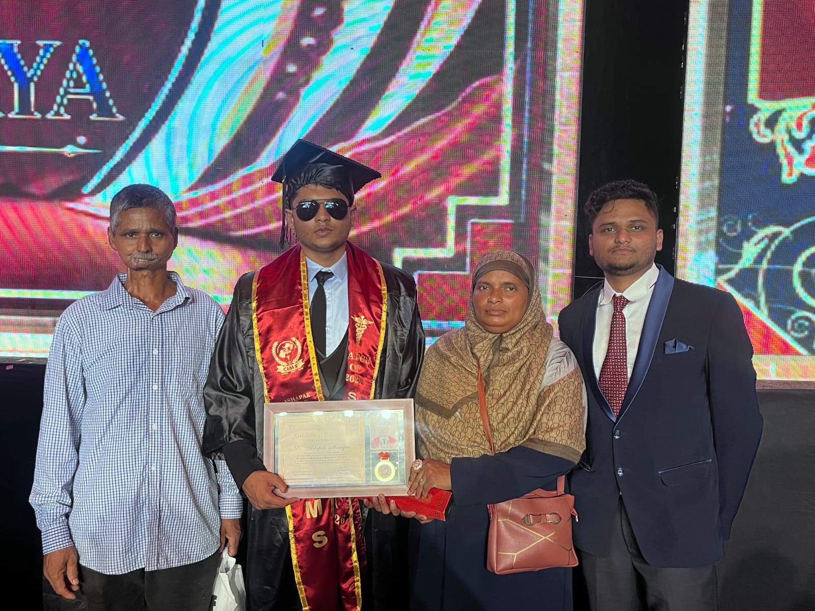 Dr. Ashpak M Manigar at his MBBS graduation with his parents and brother, holding his certificate and medal