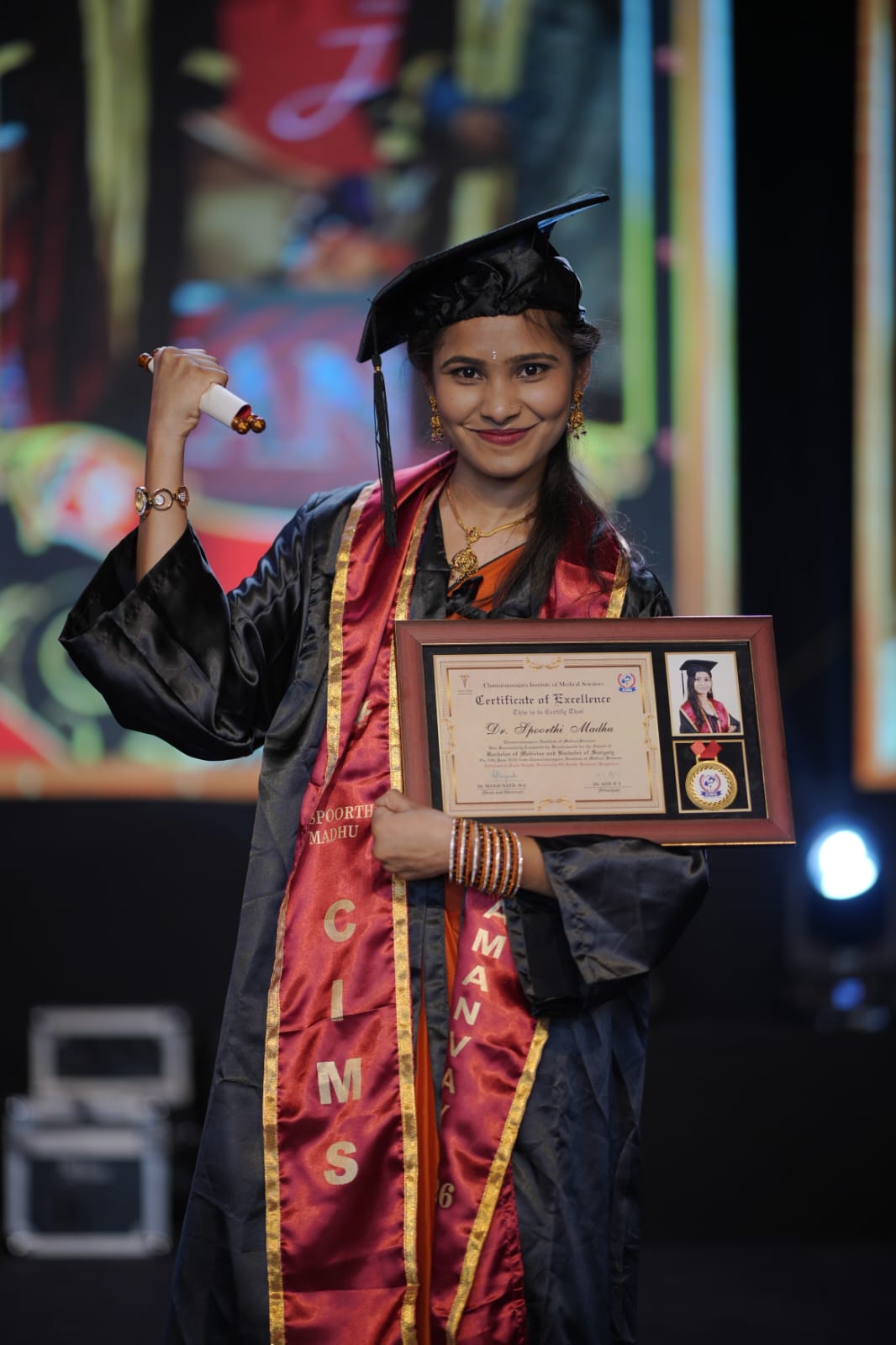 Dr. Spoorthi Madhu holding her MBBS Certificate of Excellence and medal at her graduation ceremony