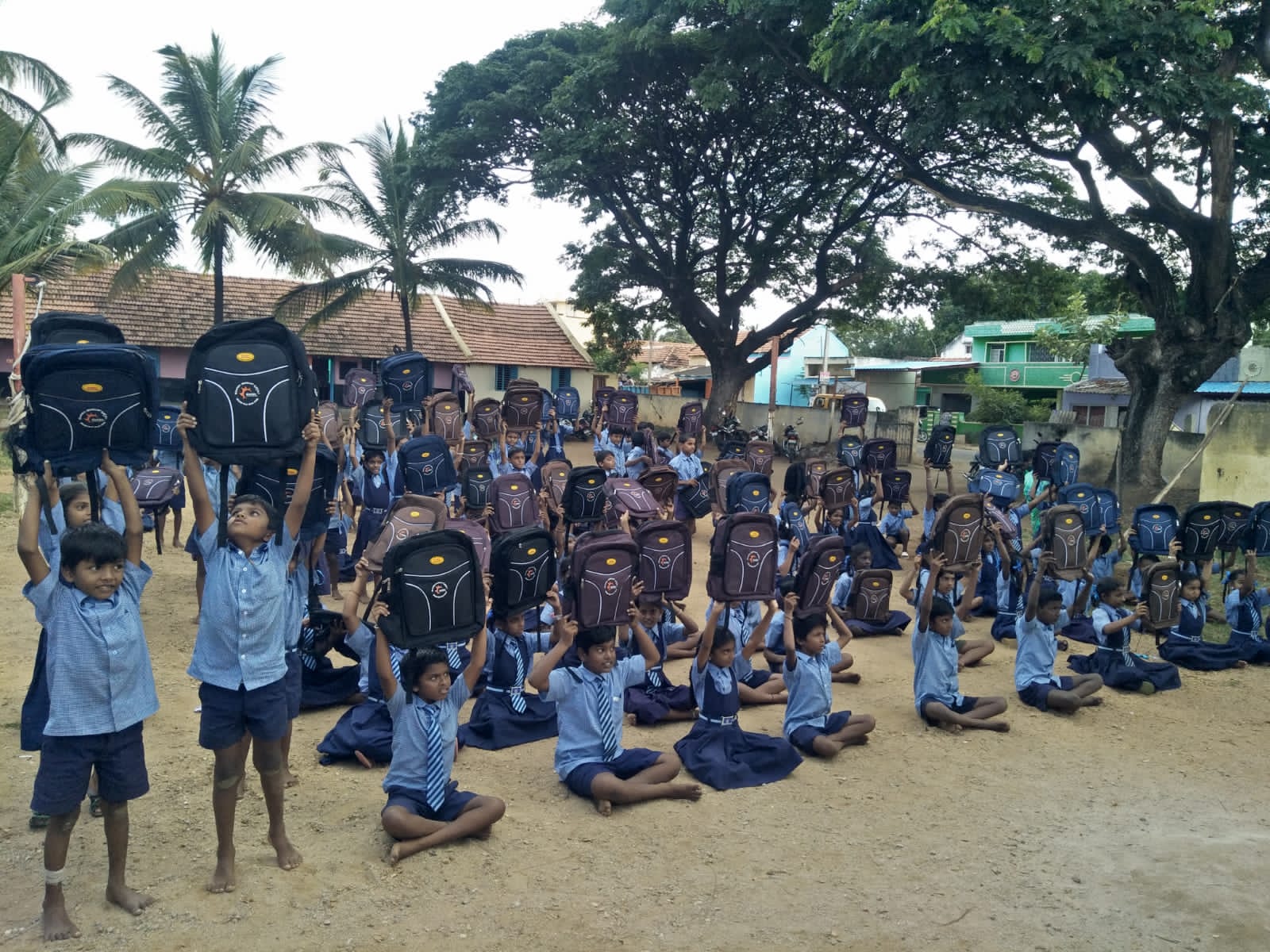 Students raising their new school bags in joy after the distribution drive.